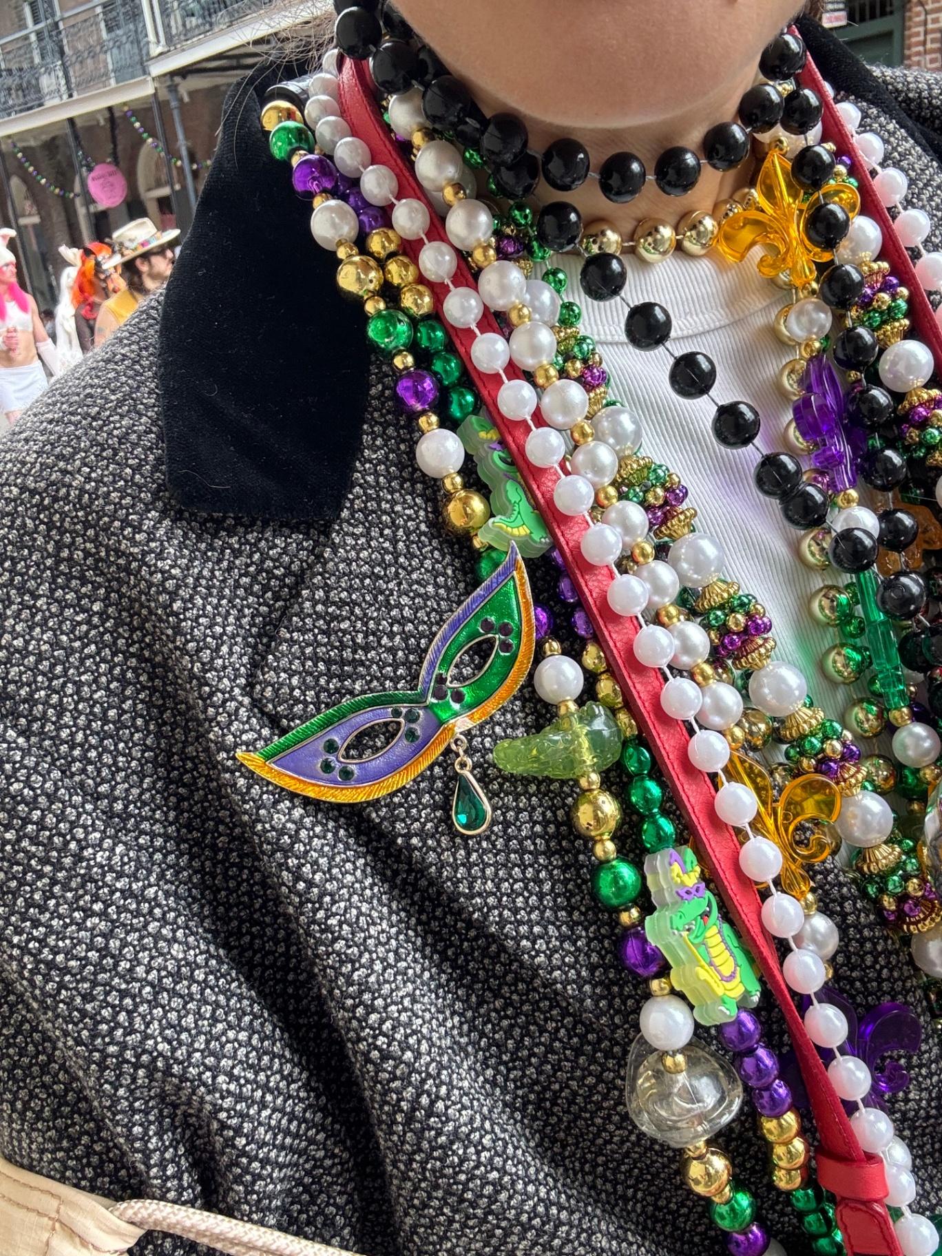 Primer plano de collares coloridos y pin de máscara en chaqueta